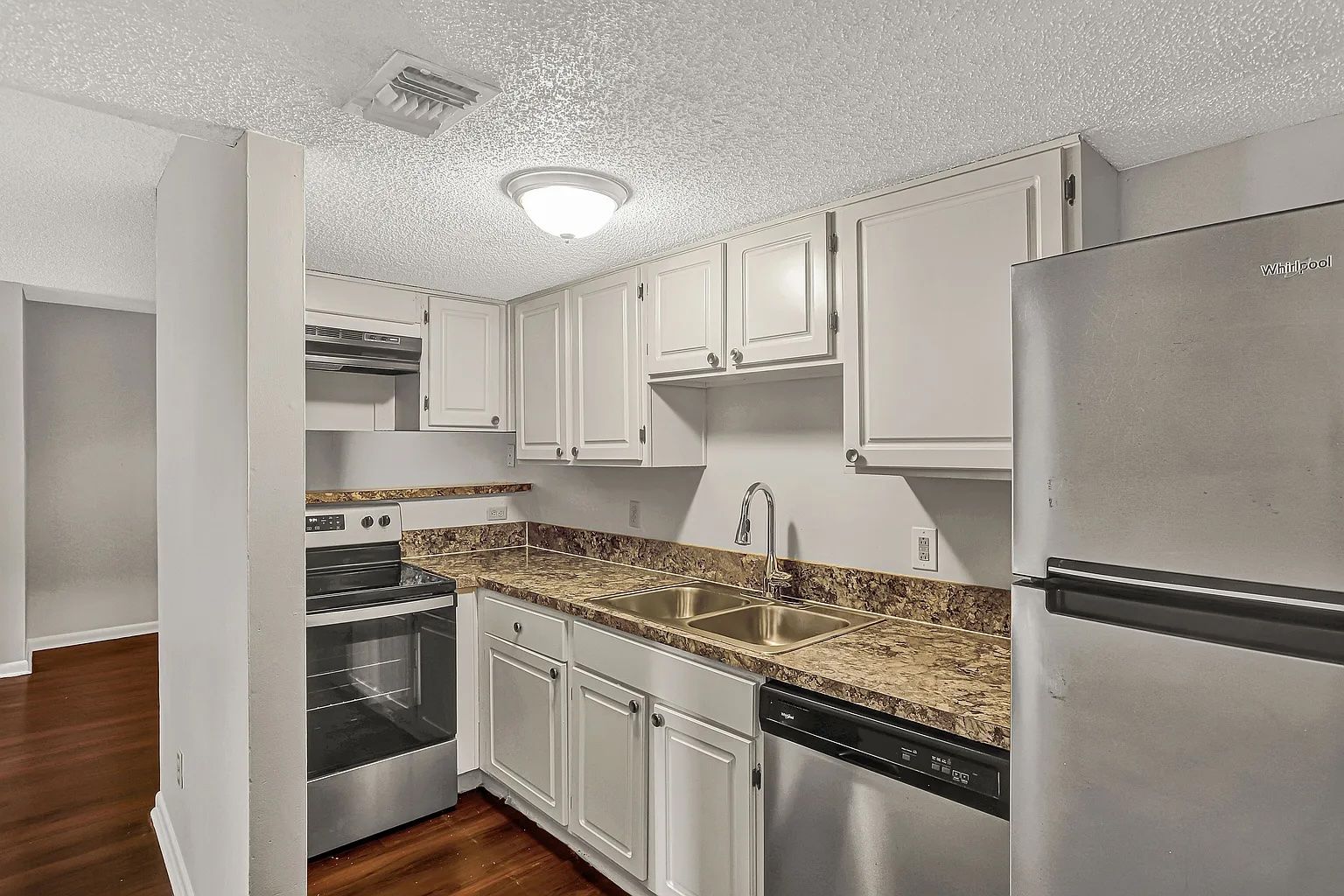 Kitchen with white cabinets, stainless steel appliances, granite countertops, and dark hardwood floors.