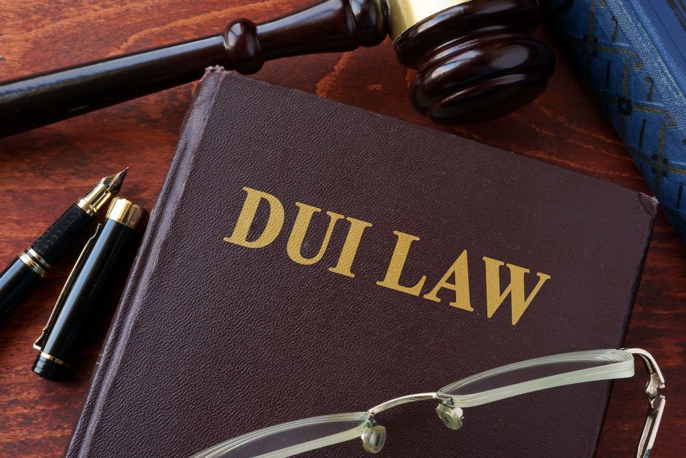 a book titled dui law is sitting on a wooden table next to a pen and glasses .