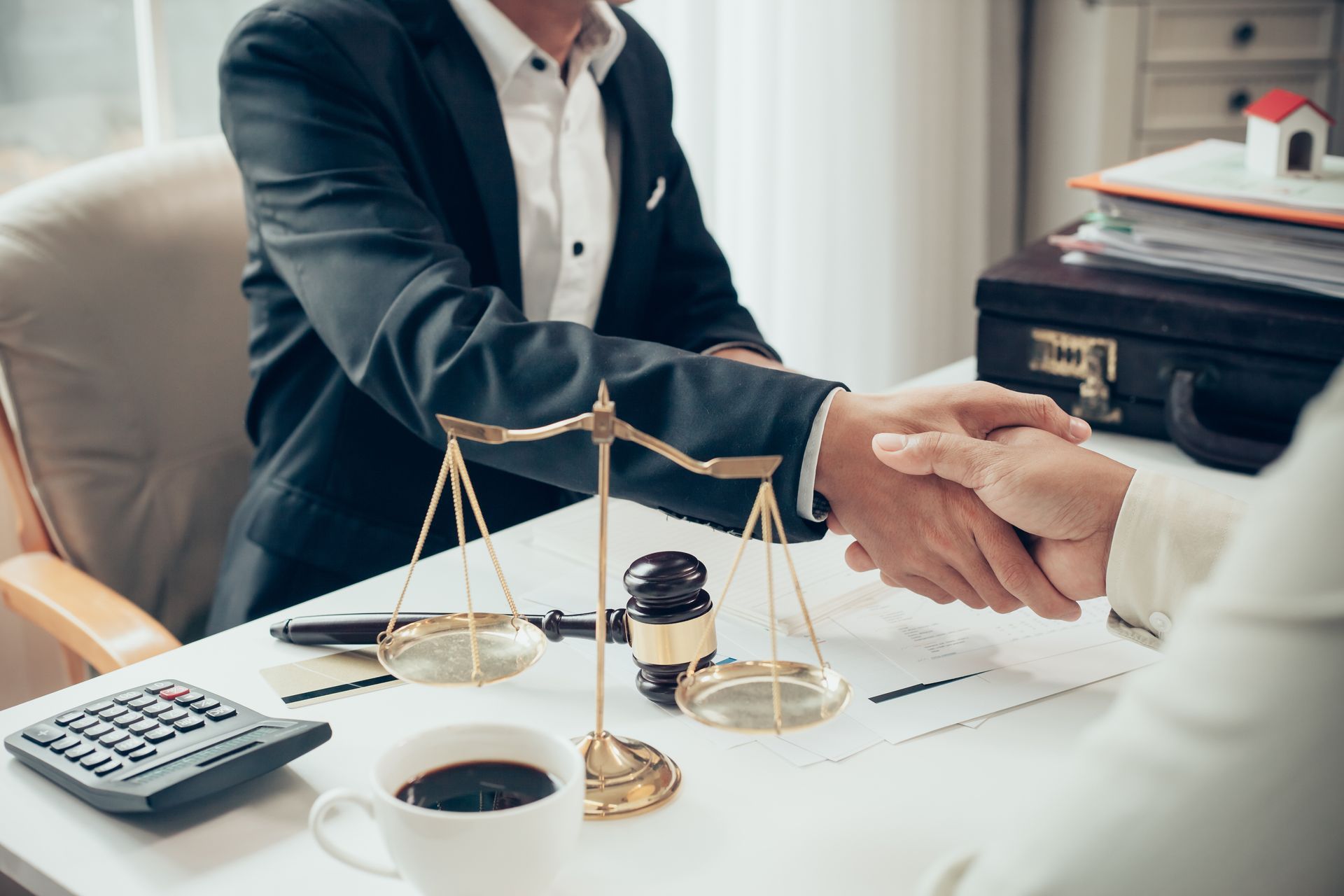 a man and woman are shaking hands over a table with scales of justice .
