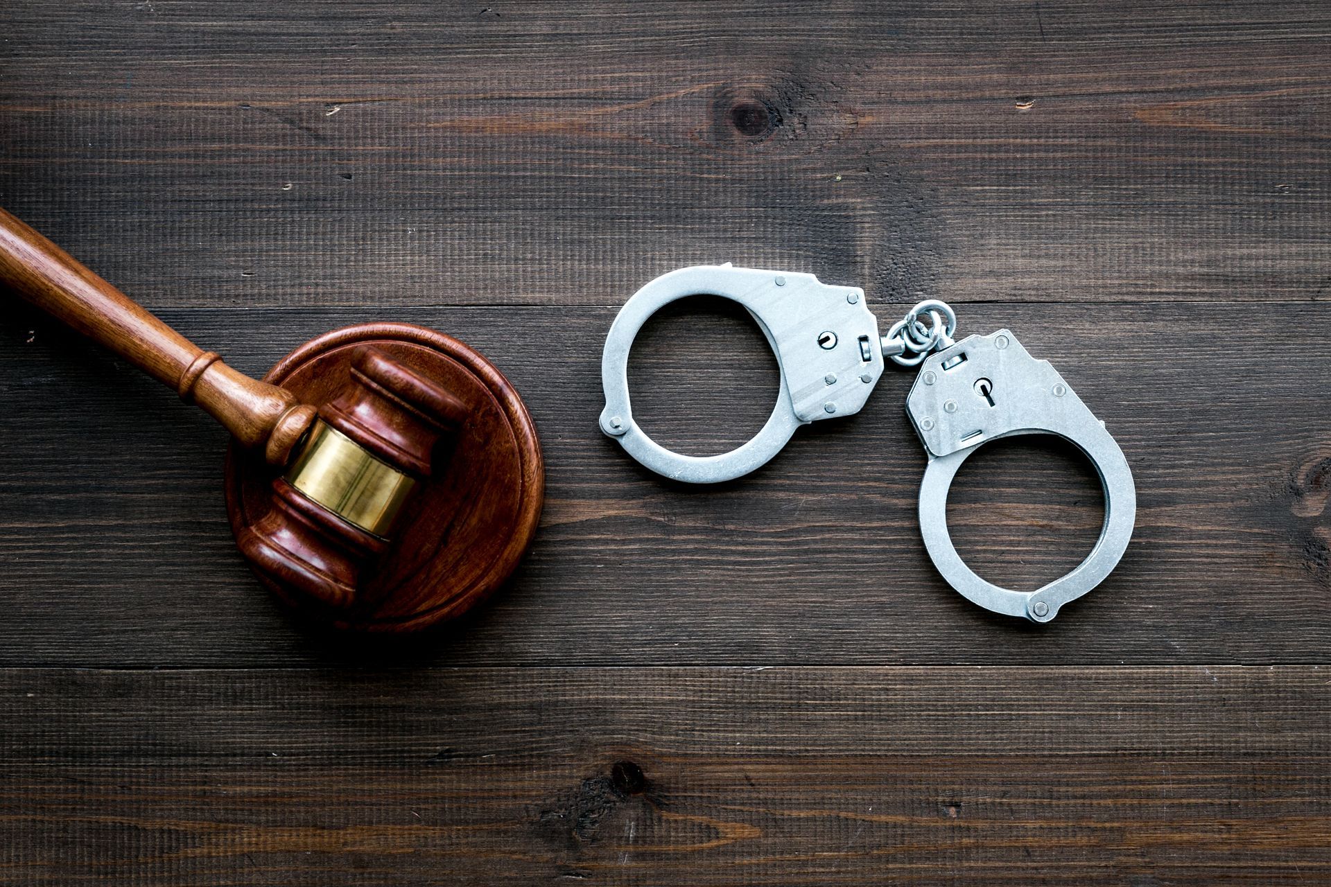 a pair of handcuffs and a judge 's gavel on a wooden table .