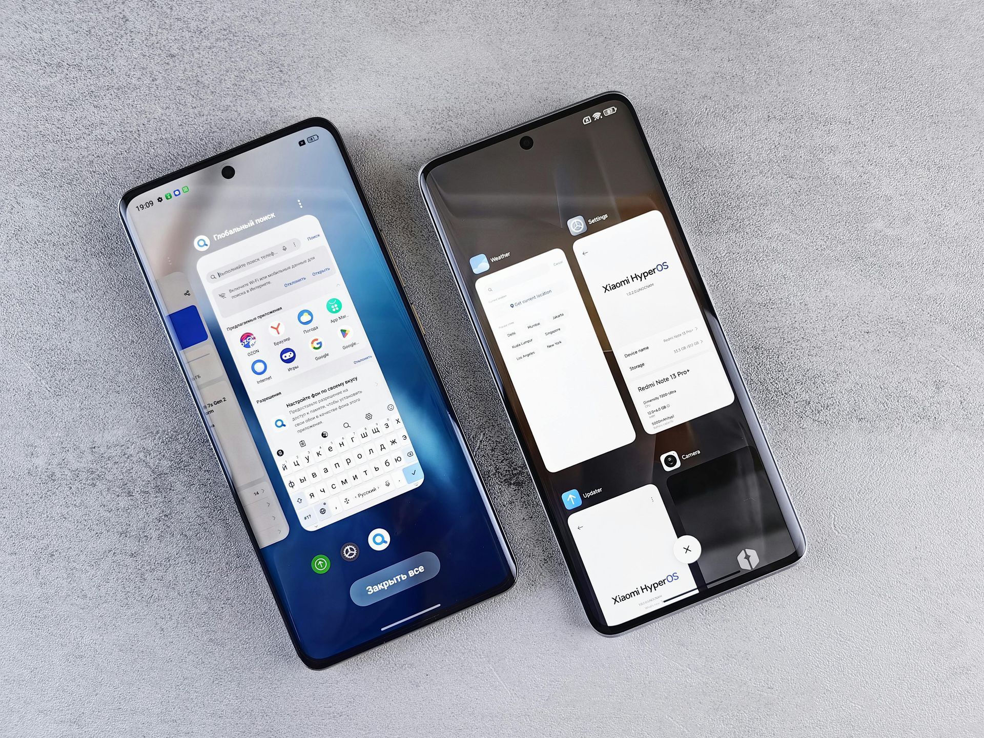 Two smartphones displaying different user interfaces on a grey surface. One shows a keyboard and app menu.