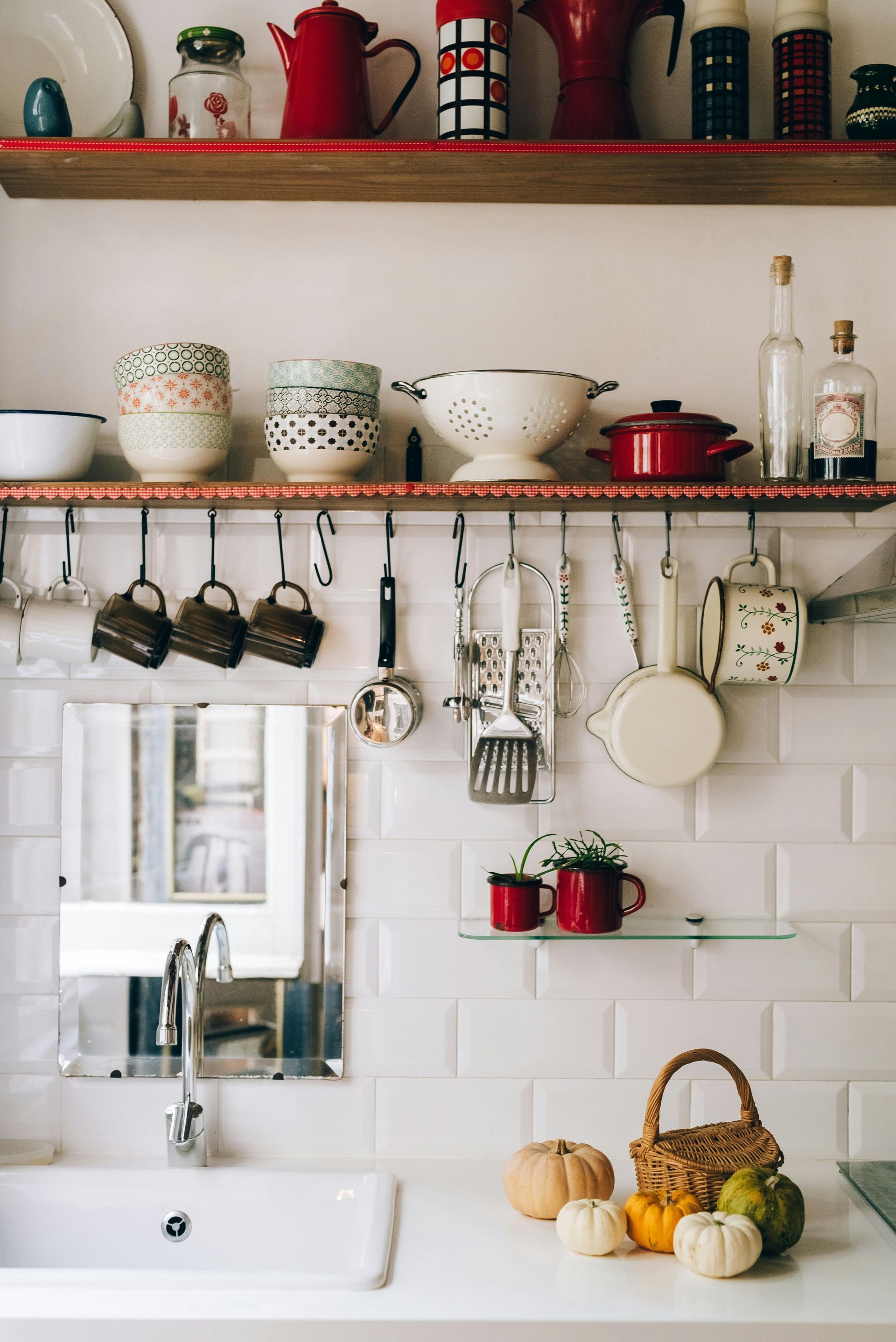Kitchen with white subway tile, open shelving displaying mugs, pots, and a basket of gourds.