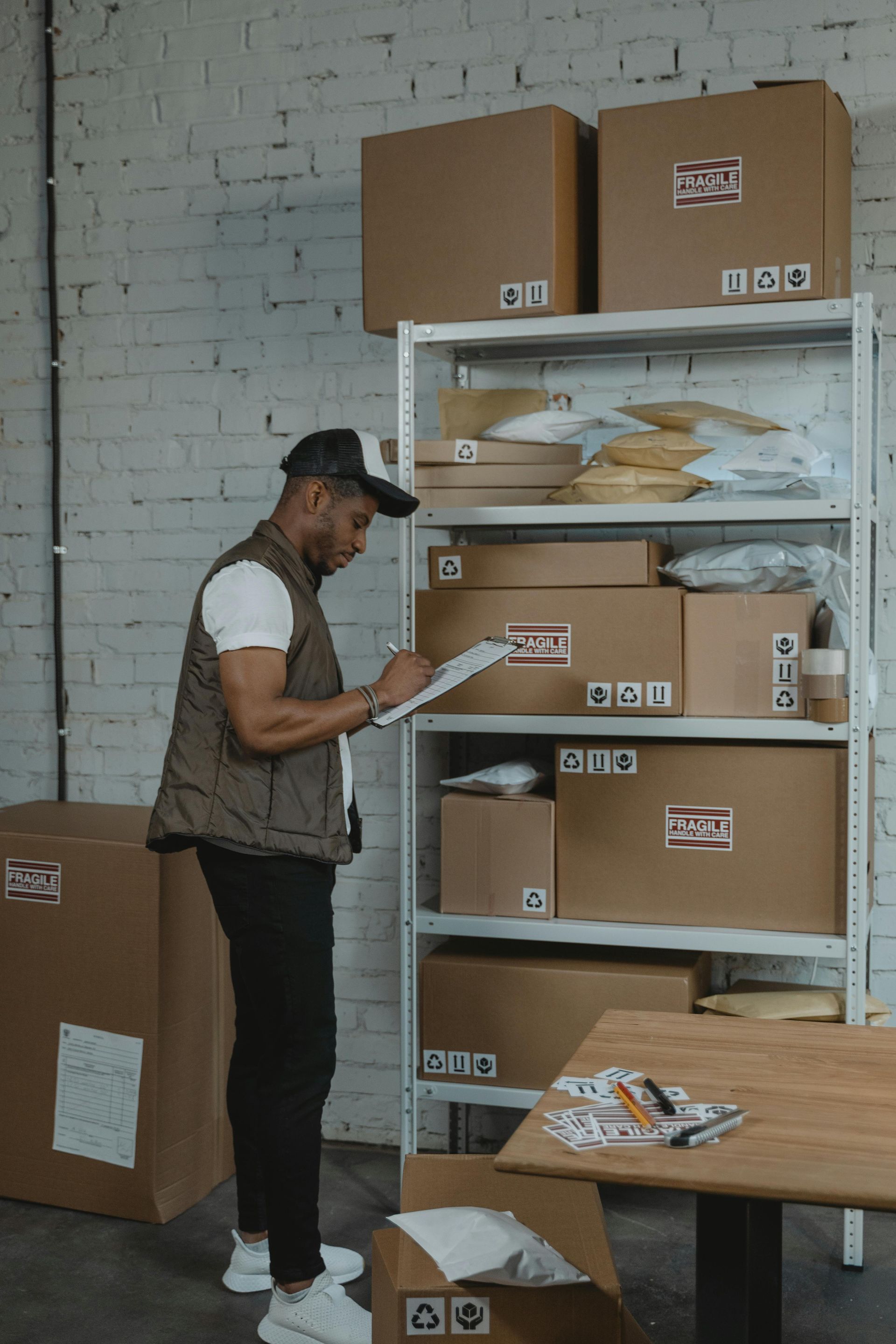Delivery worker checking packages on a shelf in a warehouse.
