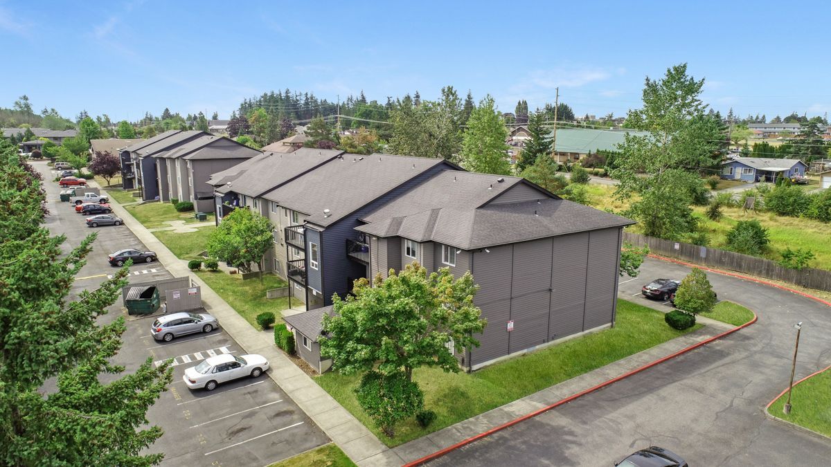 An aerial view of a row of apartment buildings with cars parked in front of them.