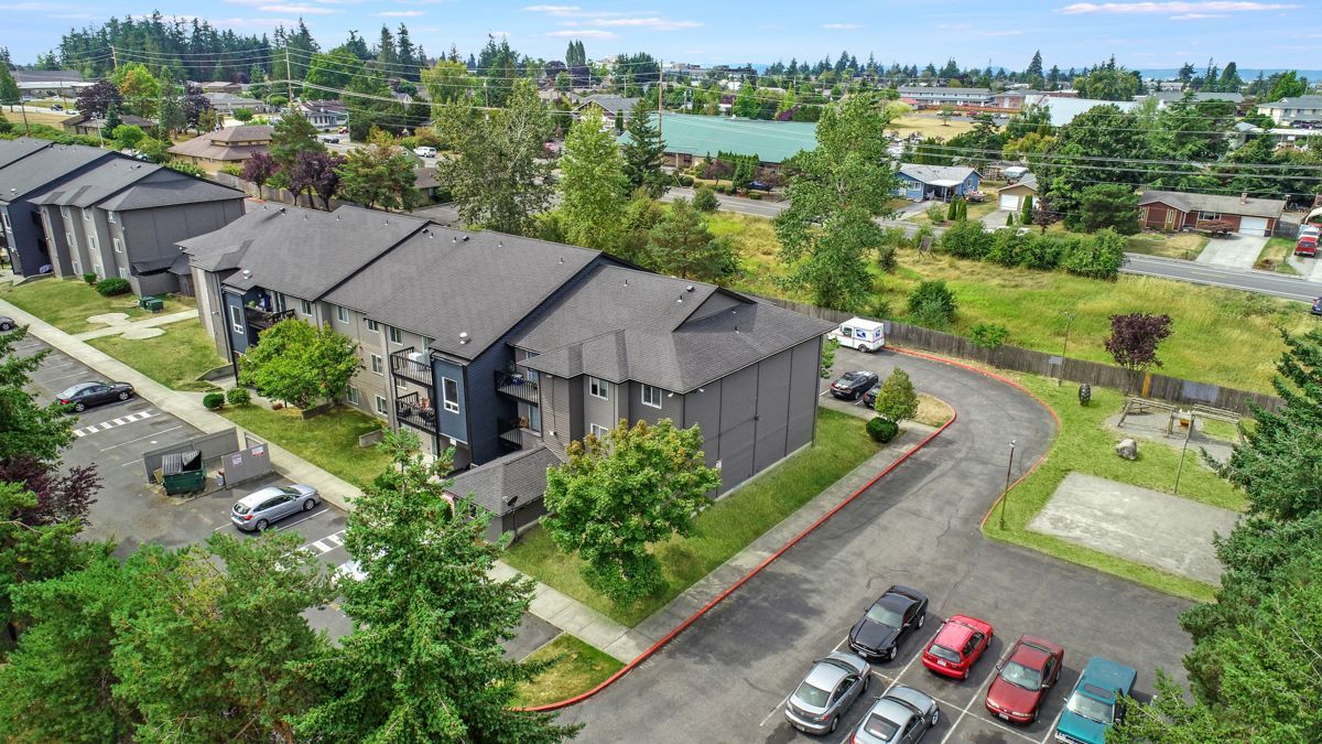 An aerial view of a apartment complex with cars parked in front of it.