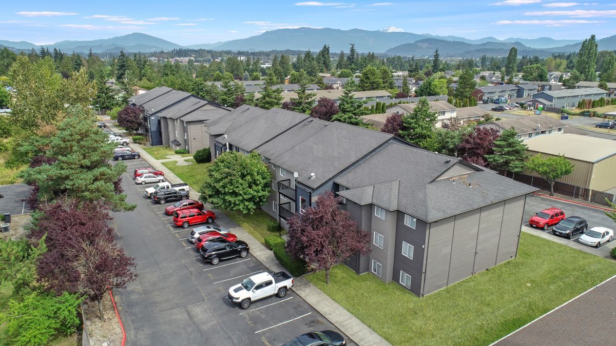 An aerial view of a row of apartment buildings with cars parked in front of them.