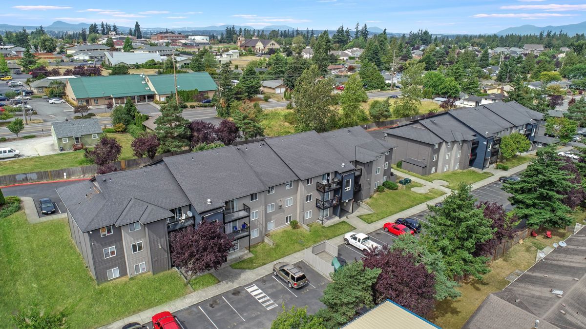 An aerial view of a row of apartment buildings with cars parked in front of them.
