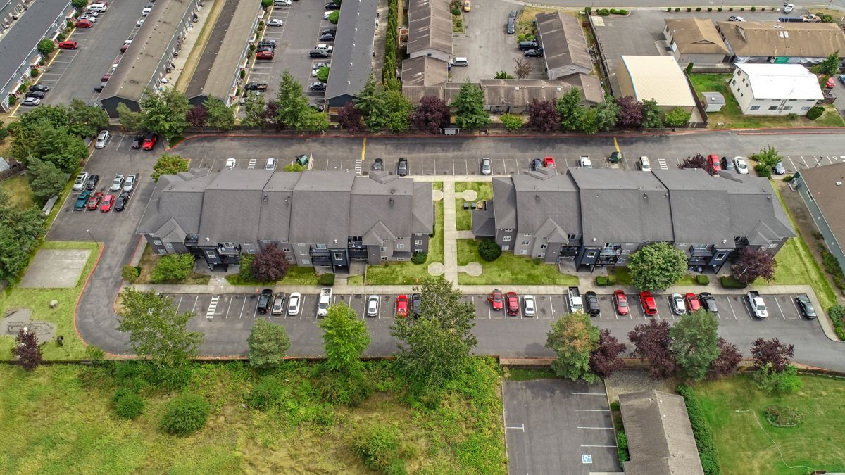 An aerial view of a row of apartment buildings with cars parked in front of them.