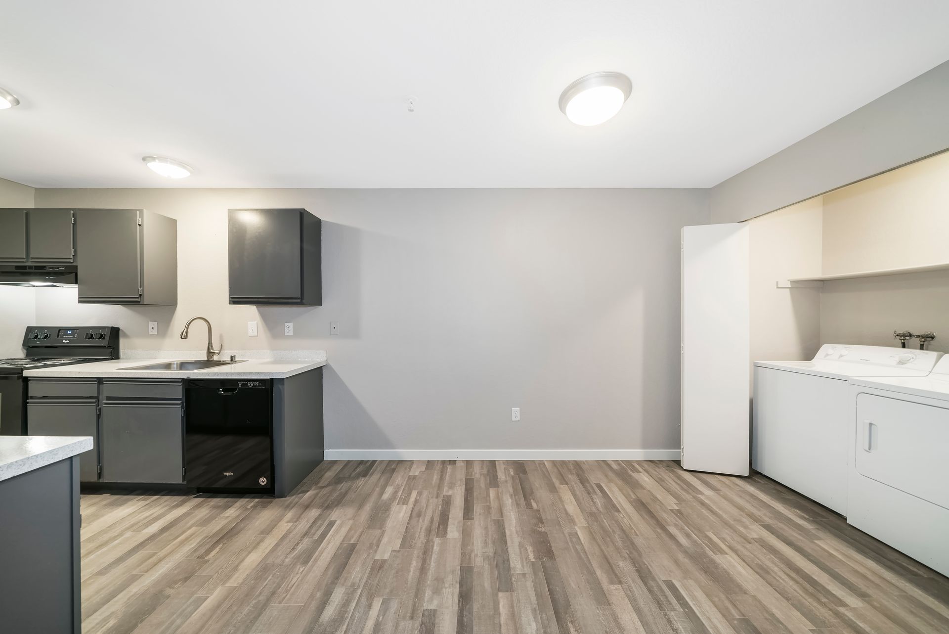 A kitchen with a stove , sink , dishwasher and washer and dryer.