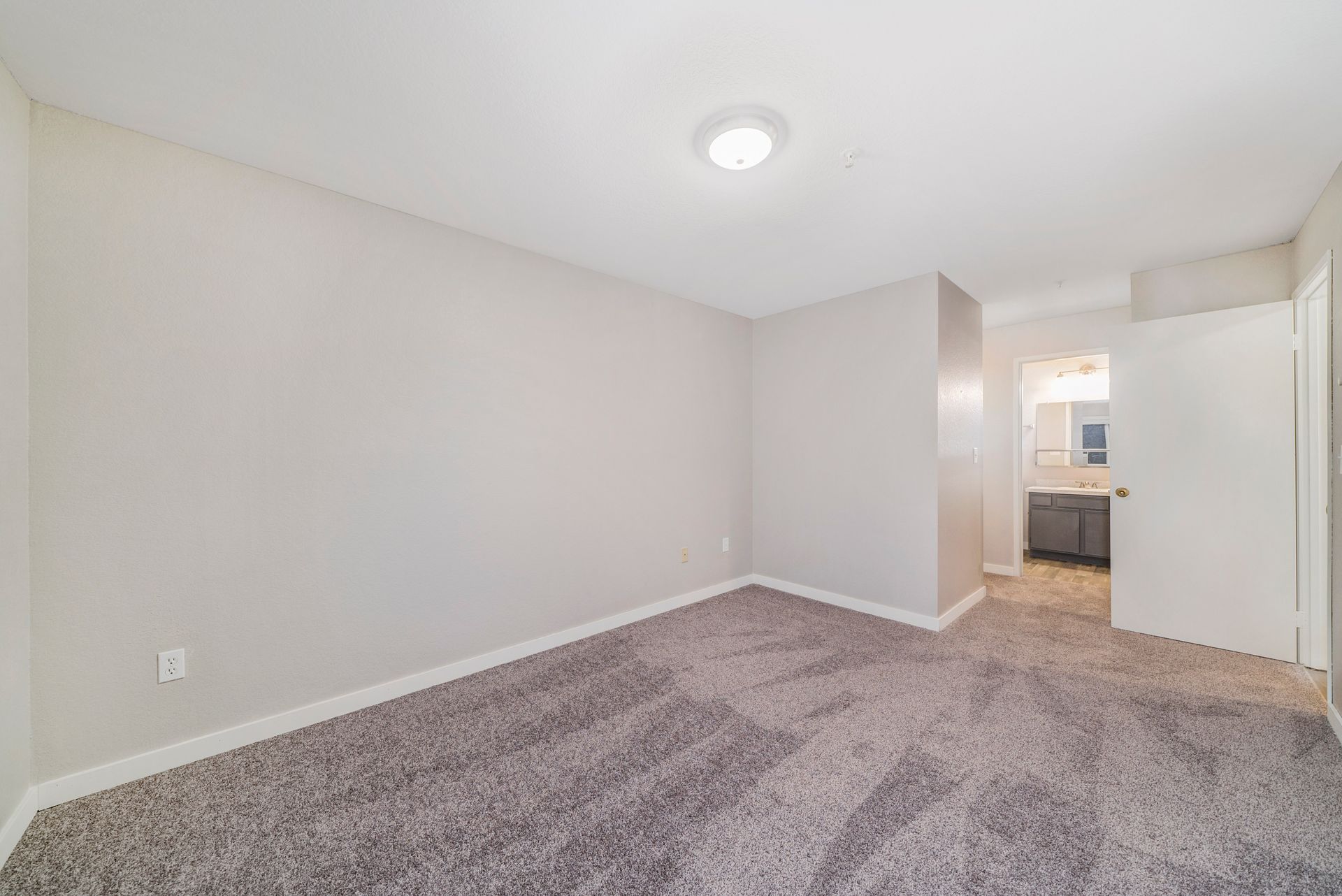 An empty bedroom with a carpeted floor and white walls.