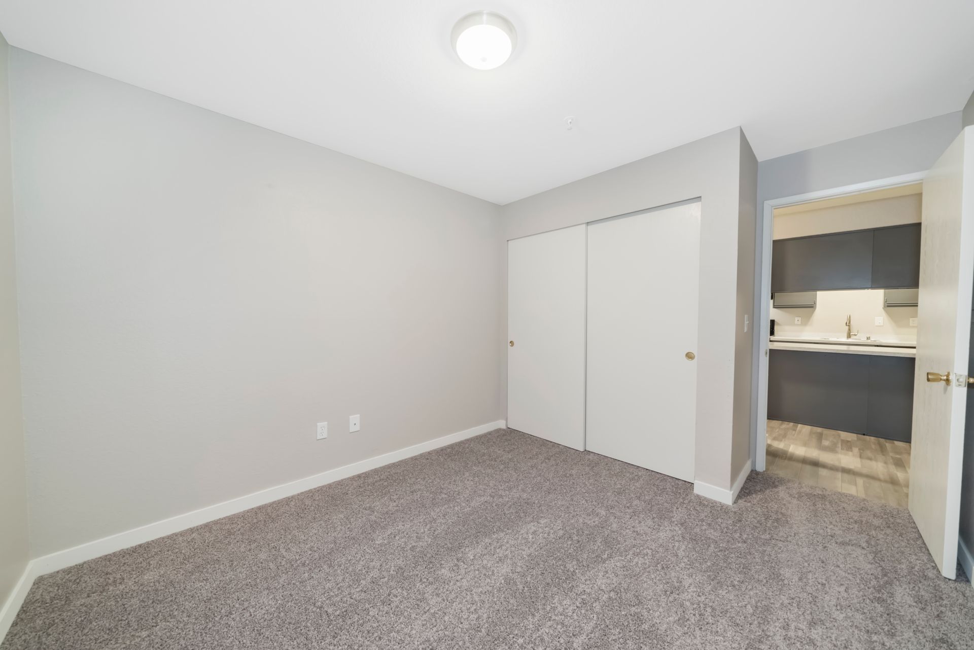 An empty bedroom with a carpeted floor and a closet.