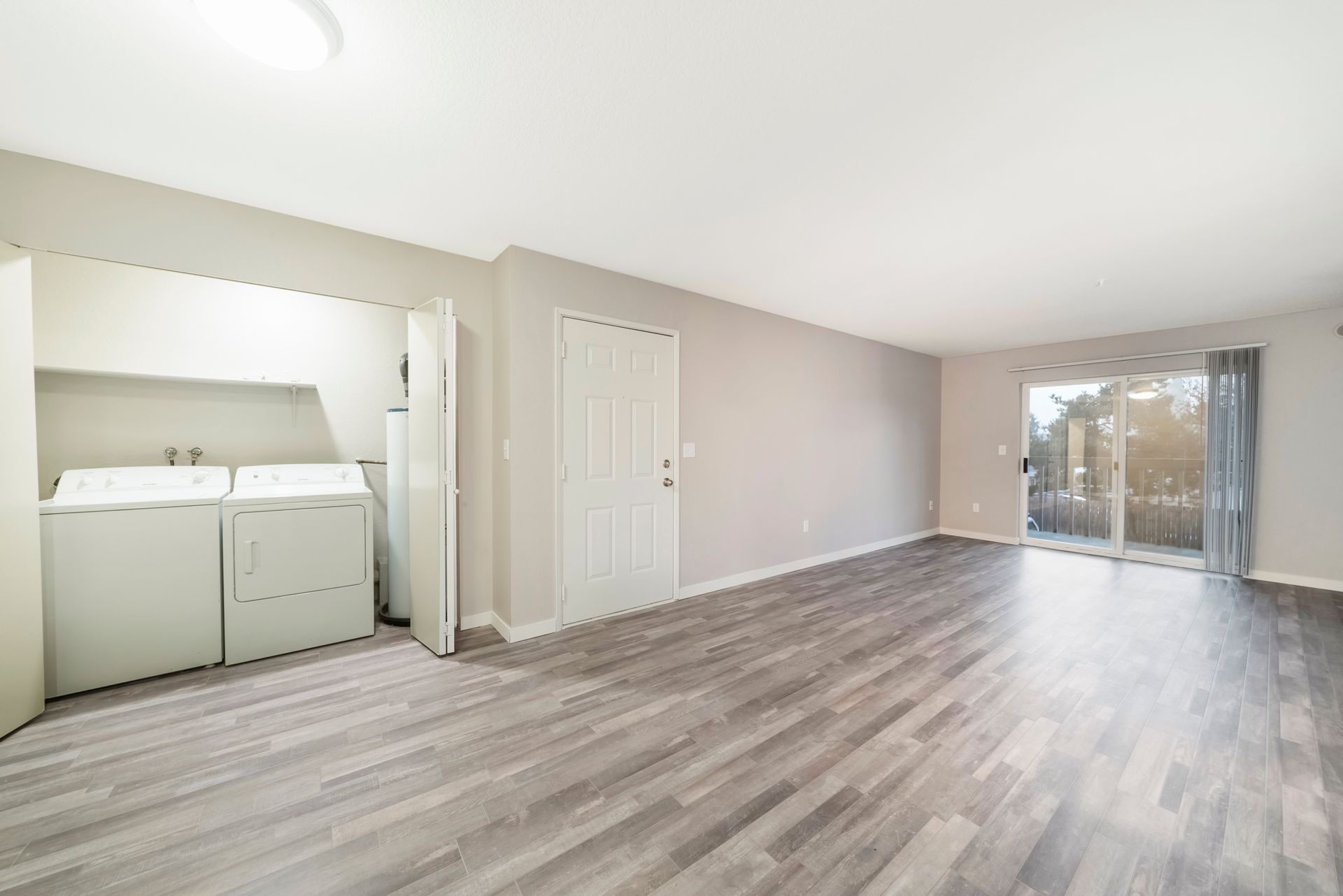A living room with a washer and dryer and a sliding glass door.