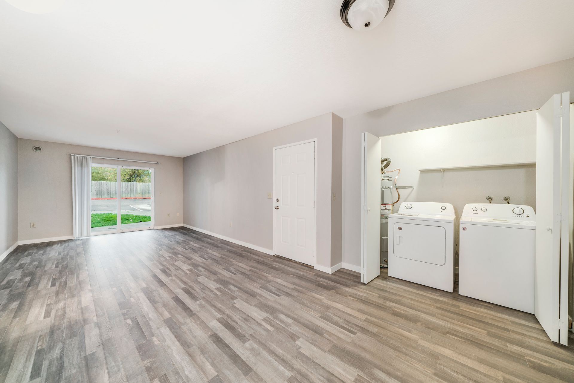 A living room with hardwood floors and a laundry room with a washer and dryer.