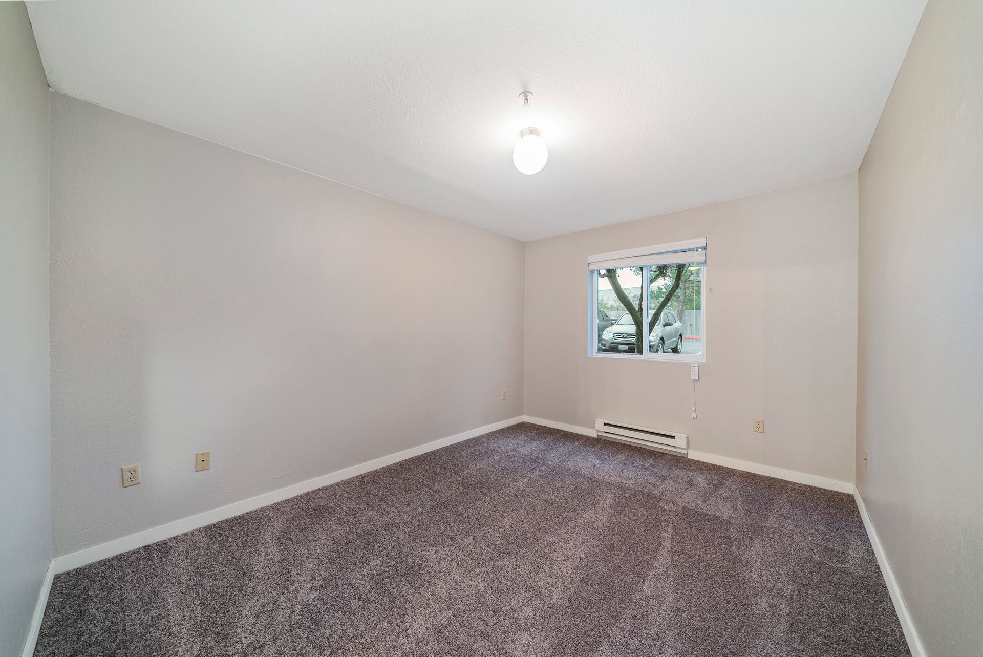 An empty bedroom with a carpeted floor and a window.