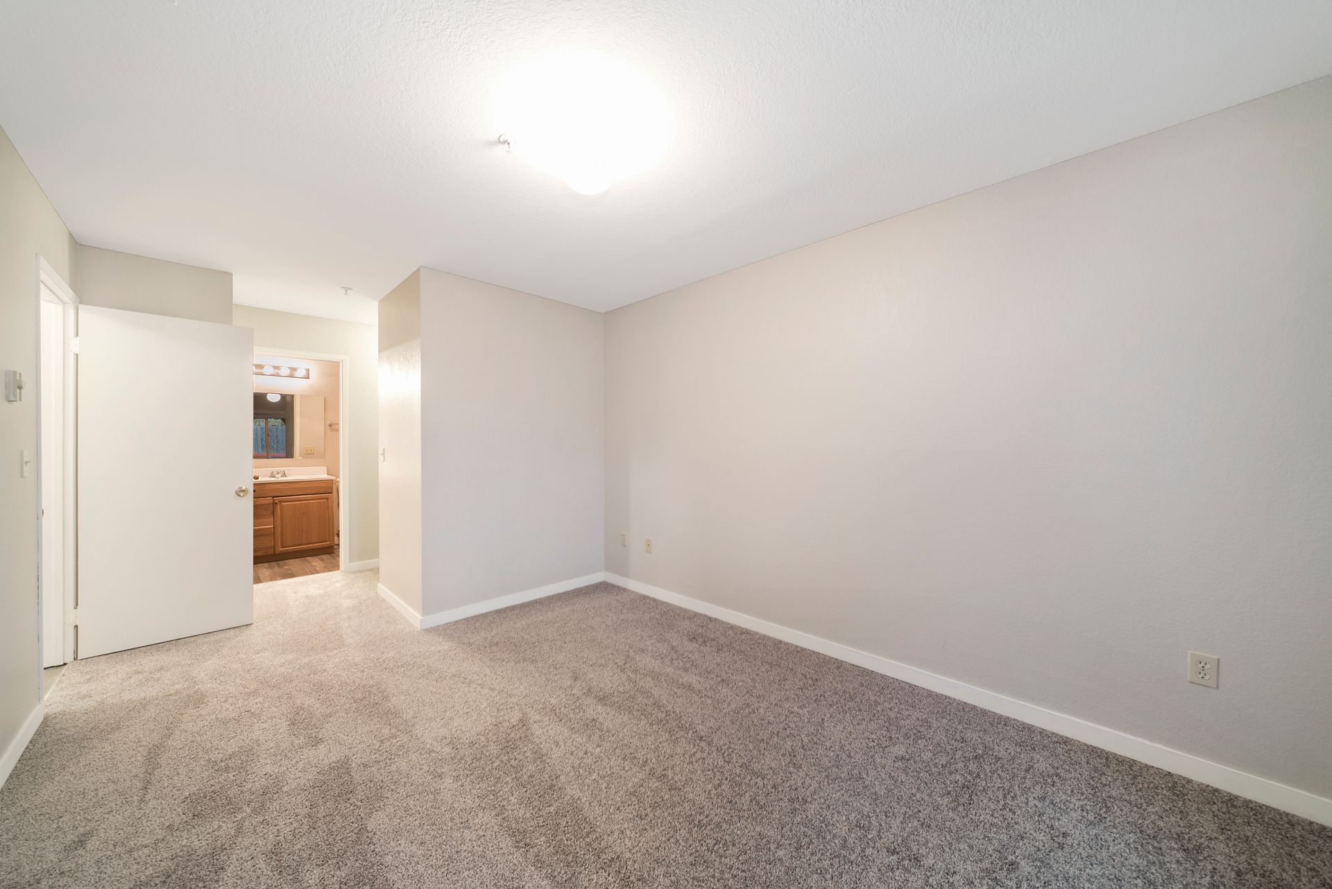 An empty bedroom with a carpeted floor and white walls.