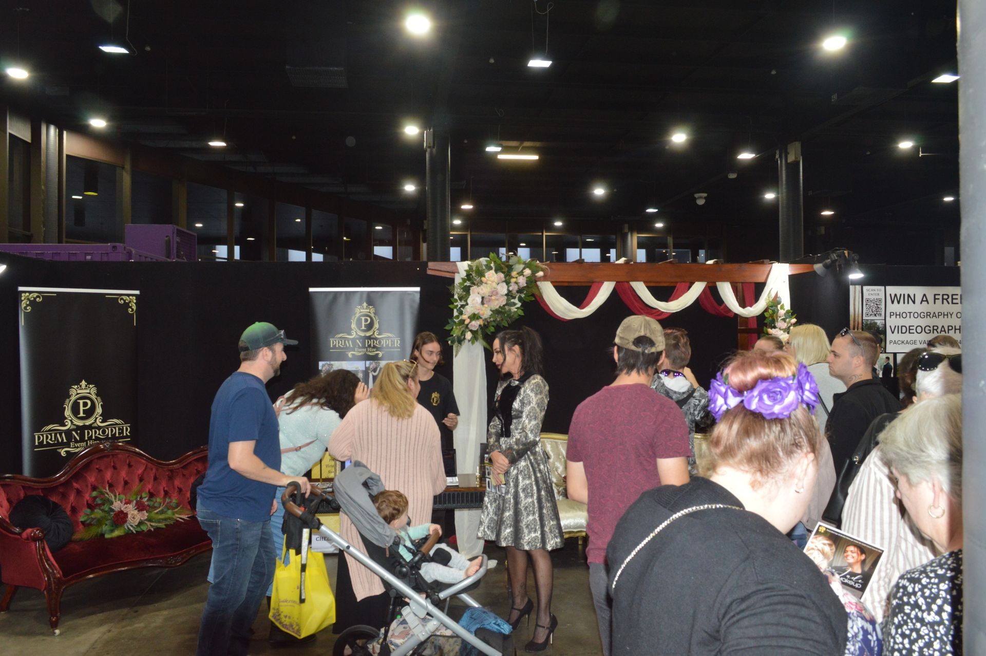 A Group of People Are Standing Around a Booth at a Convention — Prim n Proper Event Hire in Palmview, QLD