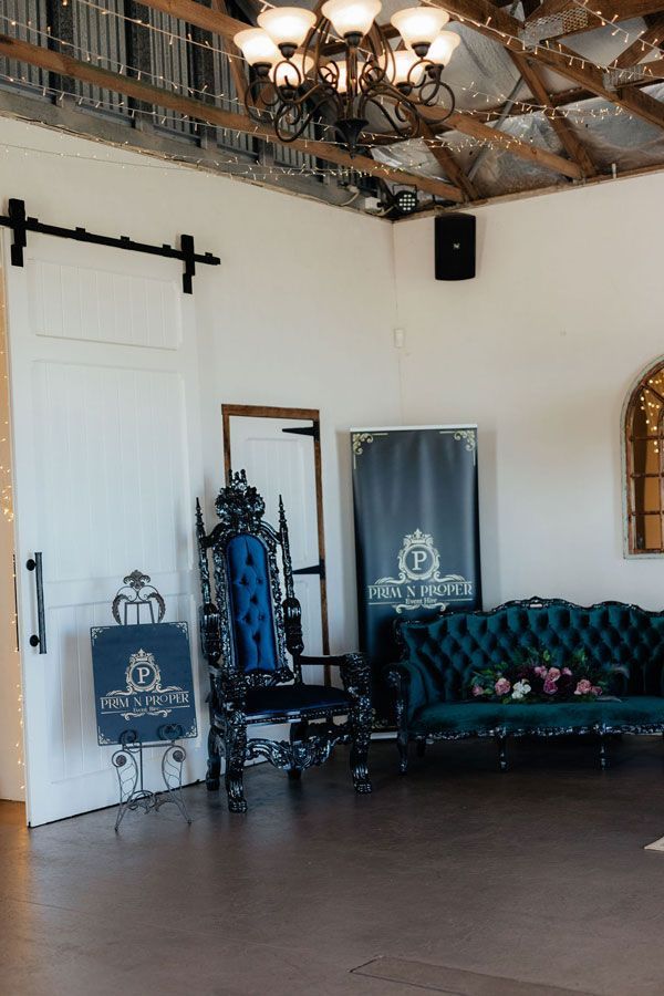 A Living Room With a Couch, Chair, Mirror and Chandelier — Prim n Proper Event Hire in Palmview, QLD