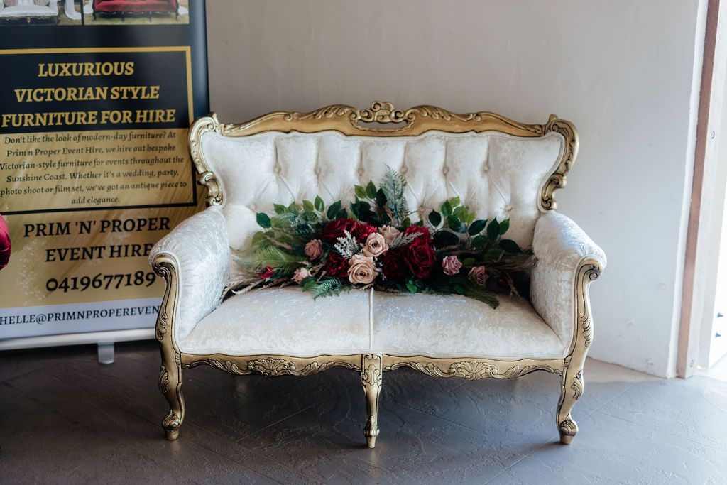 A Couch With Flowers on It in Front of a Sign — Prim n Proper Event Hire in Palmview, QLD