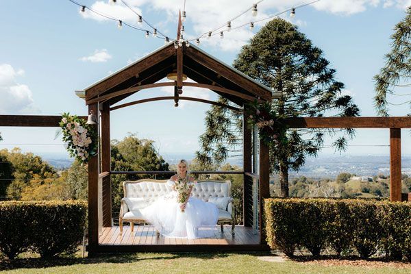 A Bride and Groom Are Sitting at a Table in a Gazebo — Prim n Proper Event Hire in Palmview, QLD