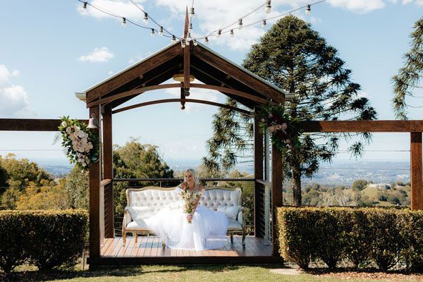 A Bride in a Wedding Dress is Sitting on a Couch in a Gazebo — Prim n Proper Event Hire in Palmview, QLD