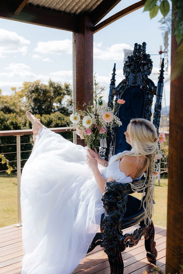 A Woman in a Wedding Dress is Sitting on a Throne on a Porch — Prim n Proper Event Hire in Palmview, QLD