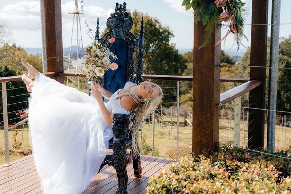 A Woman in a Wedding Dress is Laying on a Chair on a Deck — Prim n Proper Event Hire in Palmview, QLD