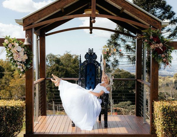 A Bride in a White Dress is Sitting on a Throne in a Gazebo — Prim n Proper Event Hire in Palmview, QLD