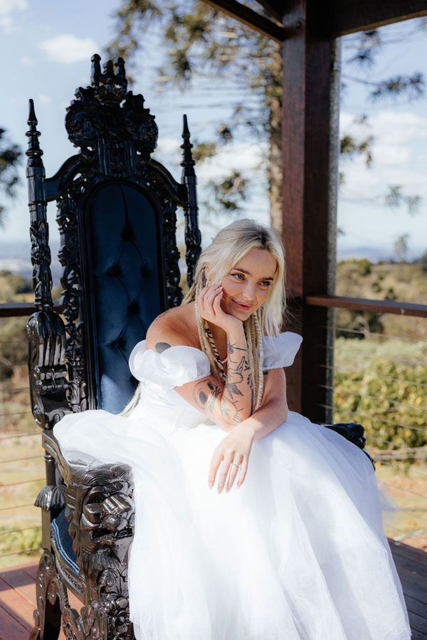 A Woman in a White Dress is Sitting on a Black Chair — Prim n Proper Event Hire in Palmview, QLD