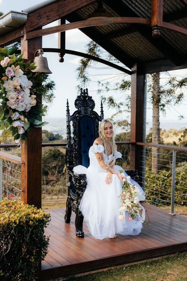 A Bride in a White Dress is Sitting on a Throne Under a Gazebo — Prim n Proper Event Hire in Palmview, QLD