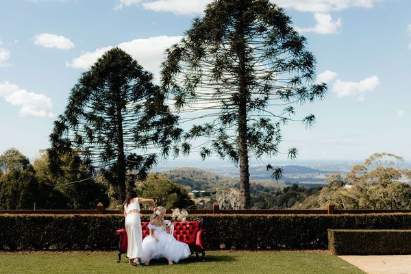 A Bride and Her Bridesmaids Are Sitting on a Bench in the Grass — Prim n Proper Event Hire in Palmview, QLD
