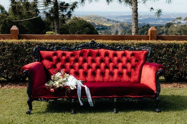 A Red Couch With a Bouquet of Flowers on It is Sitting in the Grass — Prim n Proper Event Hire in Palmview, QLD