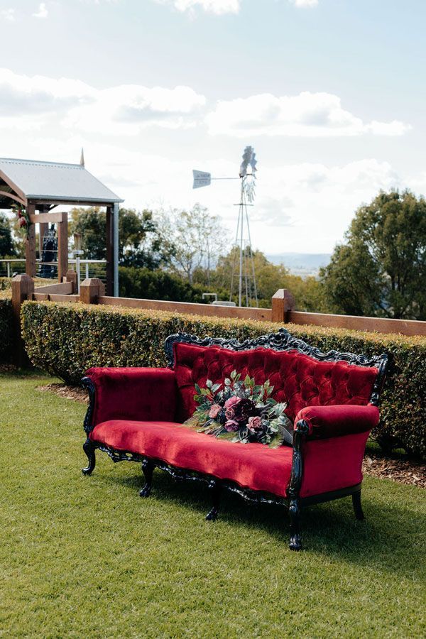 A Red Couch is Sitting on Top of a Lush Green Field — Prim n Proper Event Hire in Palmview, QLD