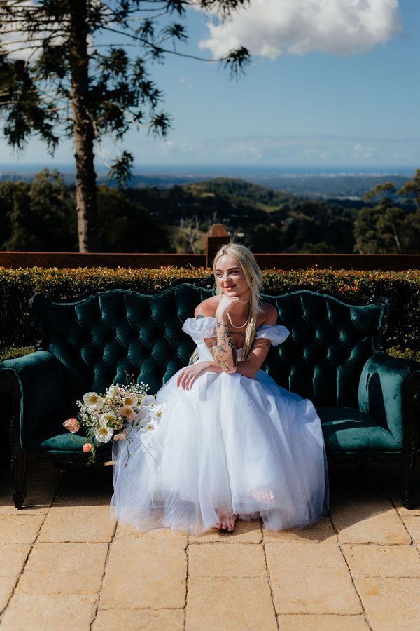 A Bride in a White Dress is Sitting on a Green Couch — Prim n Proper Event Hire in Palmview, QLD