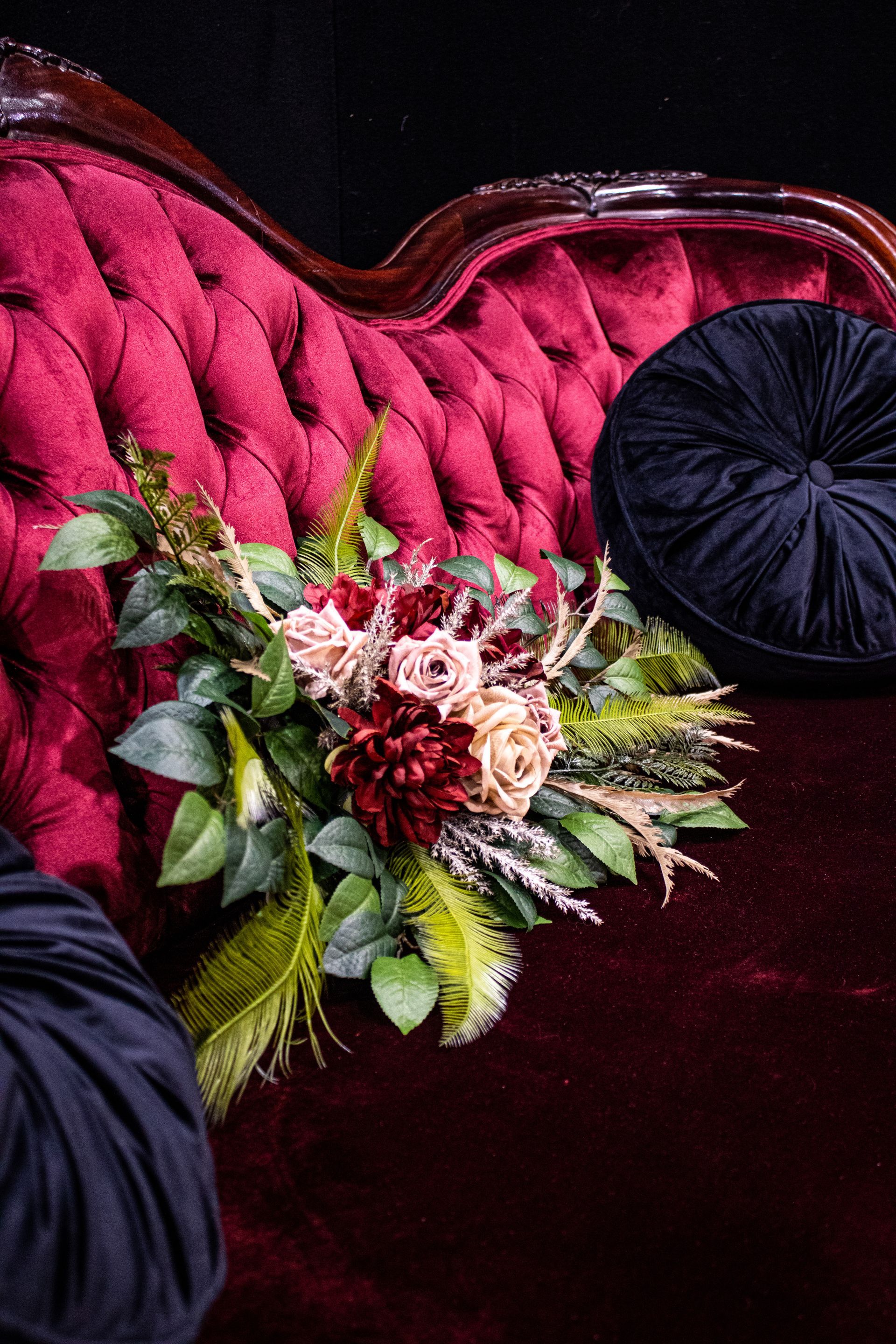 A Red Couch With a Black Pillow and Flowers on It — Prim n Proper Event Hire in Palmview, QLD