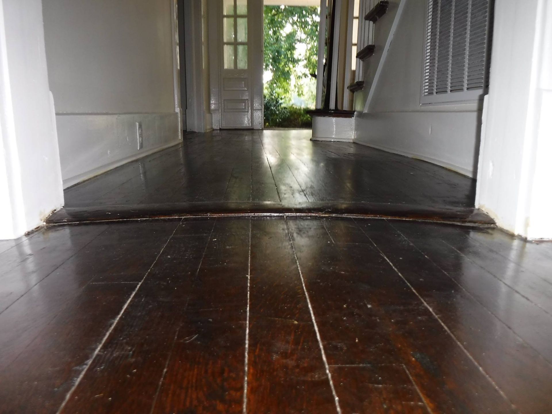 Dark wood floor with a raised threshold, leading to doors and stairs.