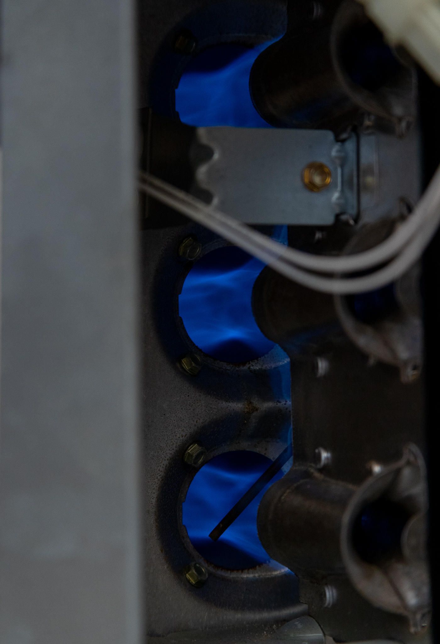 Blue flames inside a gas furnace, viewed up close.