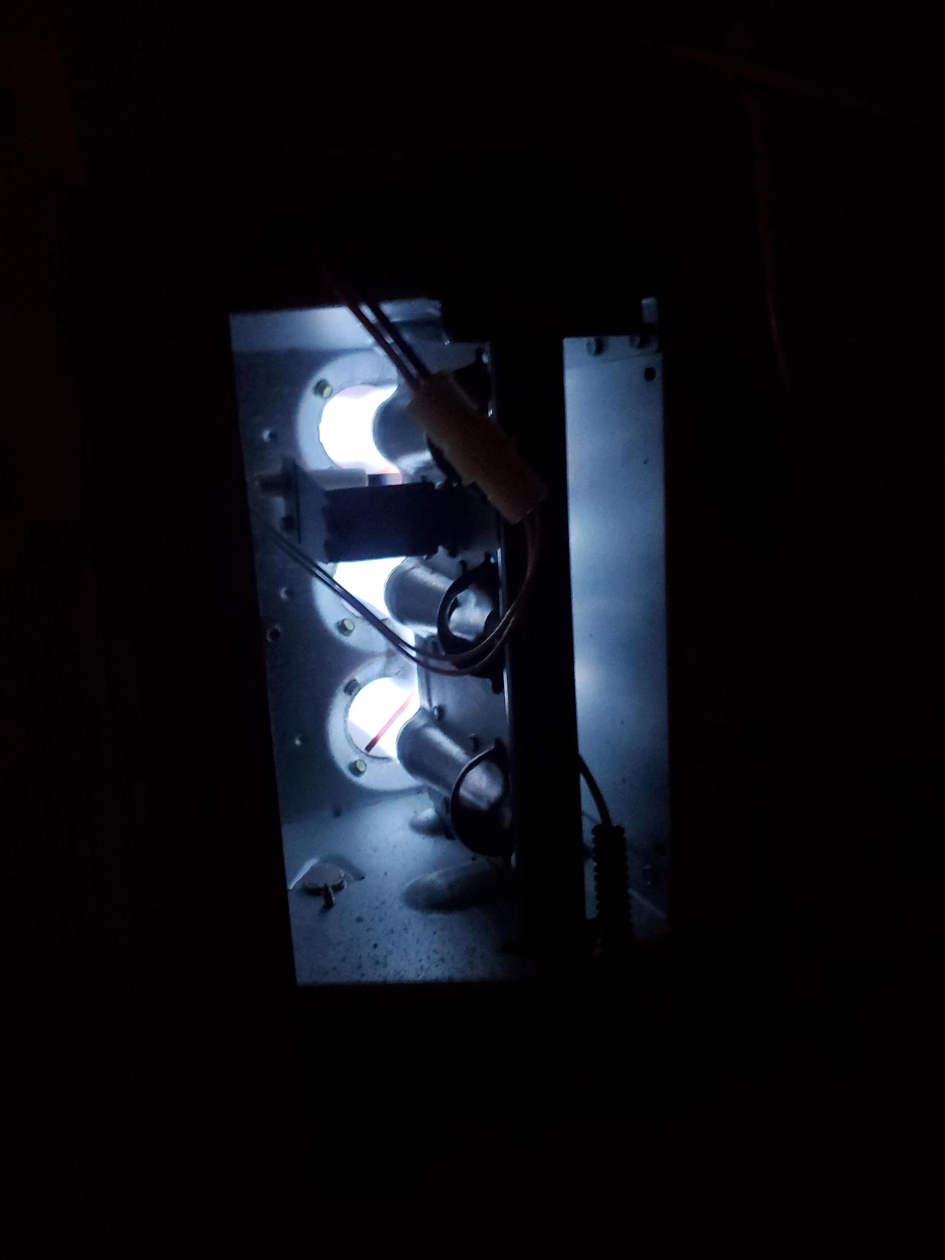 Furnace burners glowing bright blue inside a dark compartment.