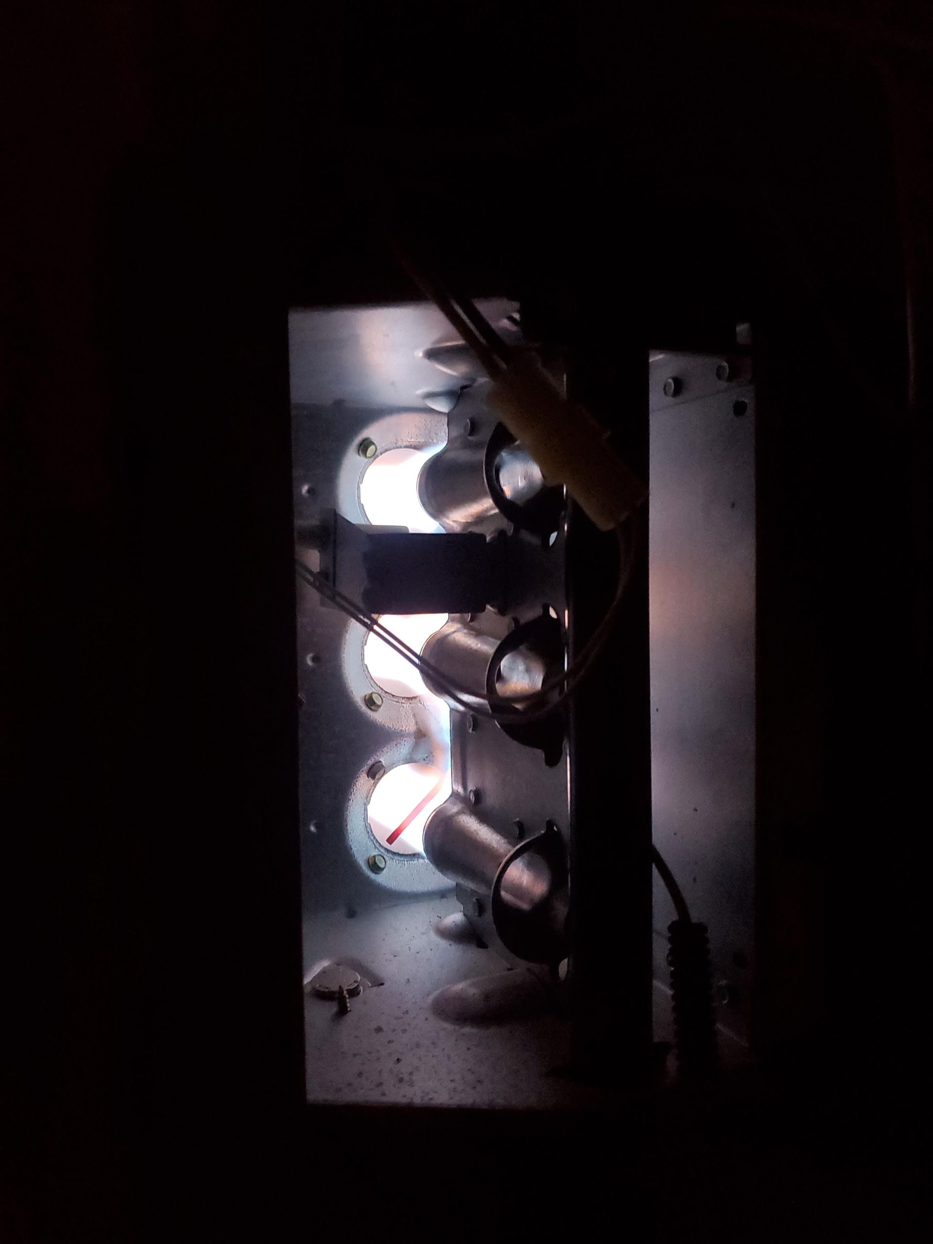 Furnace interior with three lit burners glowing orange-white; viewed from the front.