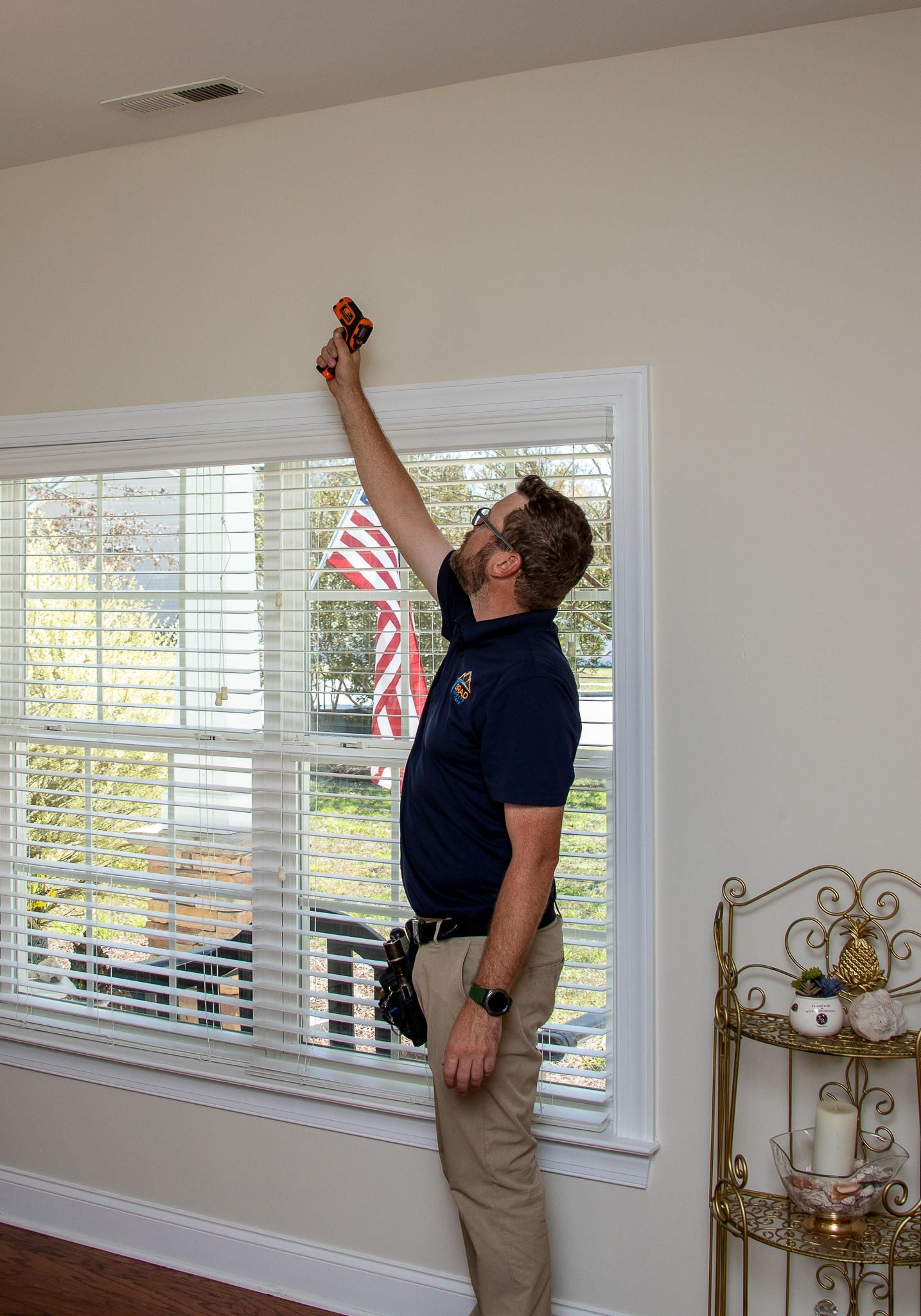 Man inspecting ceiling near window. Indoors, natural light.
