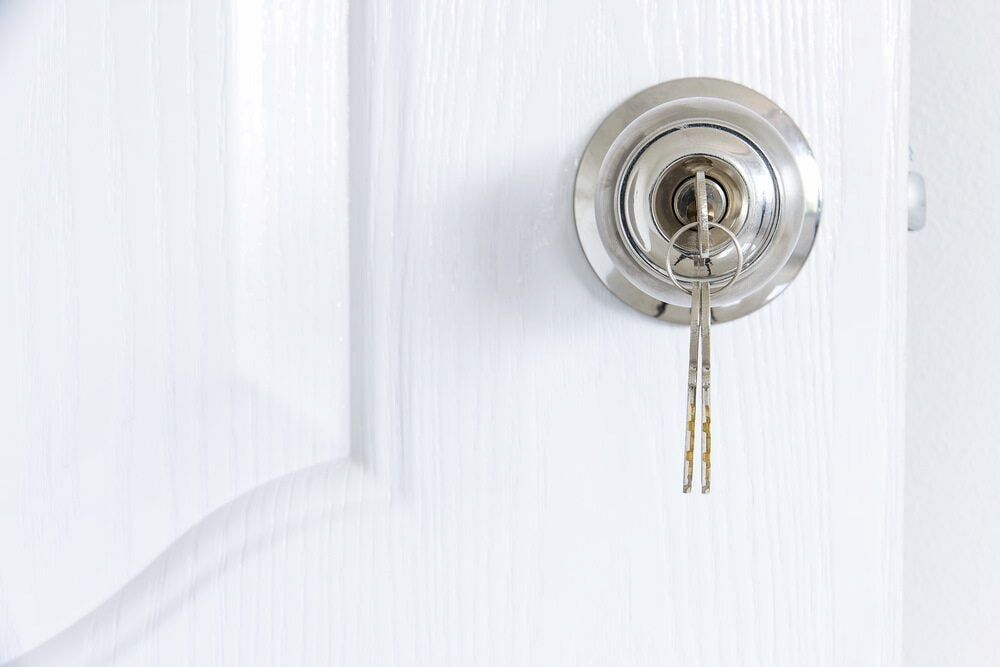White Door With a Silver Doorknob and Keys Inserted — Coast 2 Coast Locksmiths in Currimundi, QLD
