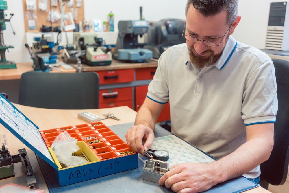 Locksmith Working on a Lock at a Workbench With Tools and Key Parts — Coast 2 Coast Locksmiths in Nambour, QLD