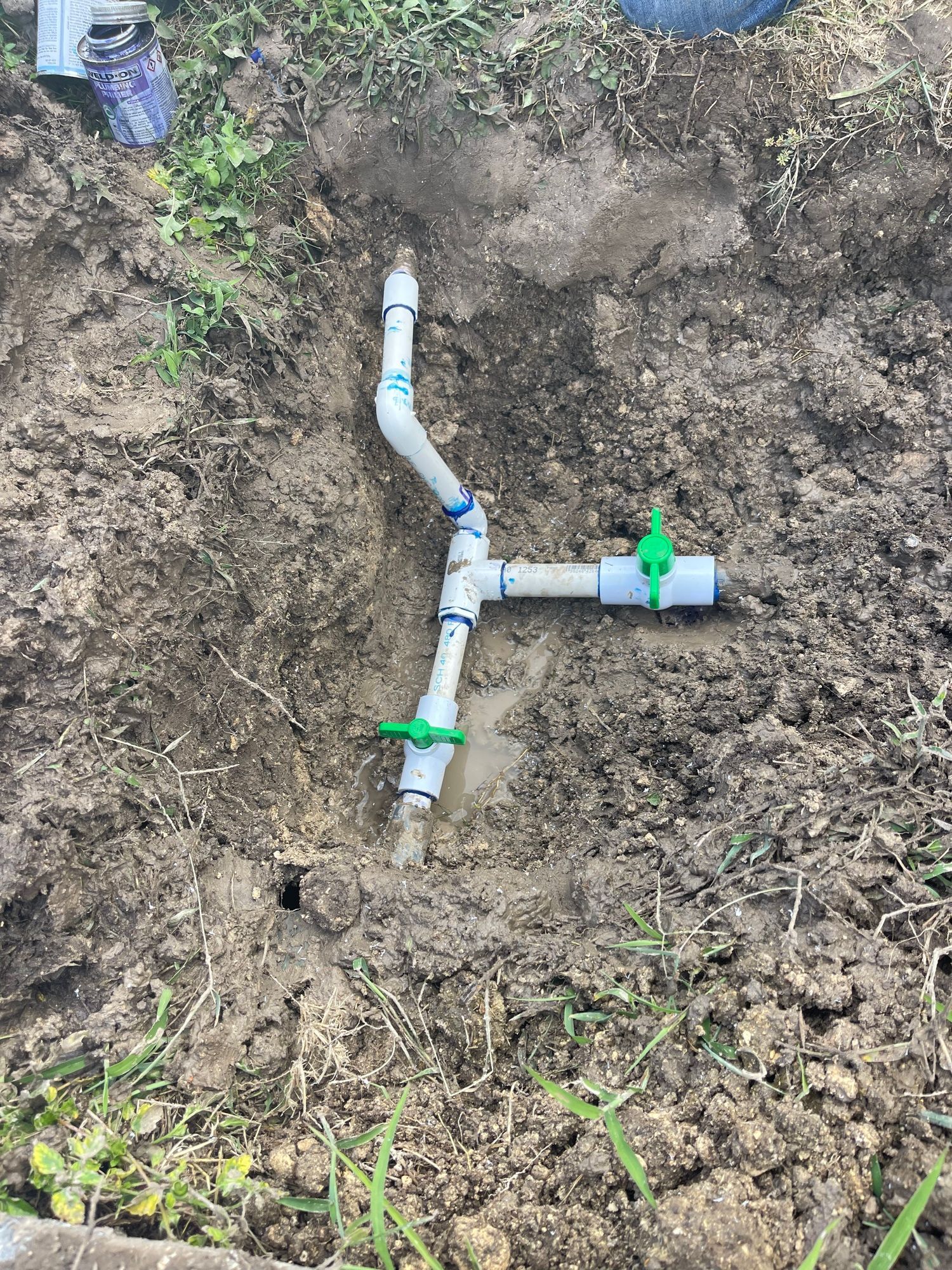 A person is digging a hole in the ground to install a sprinkler system.