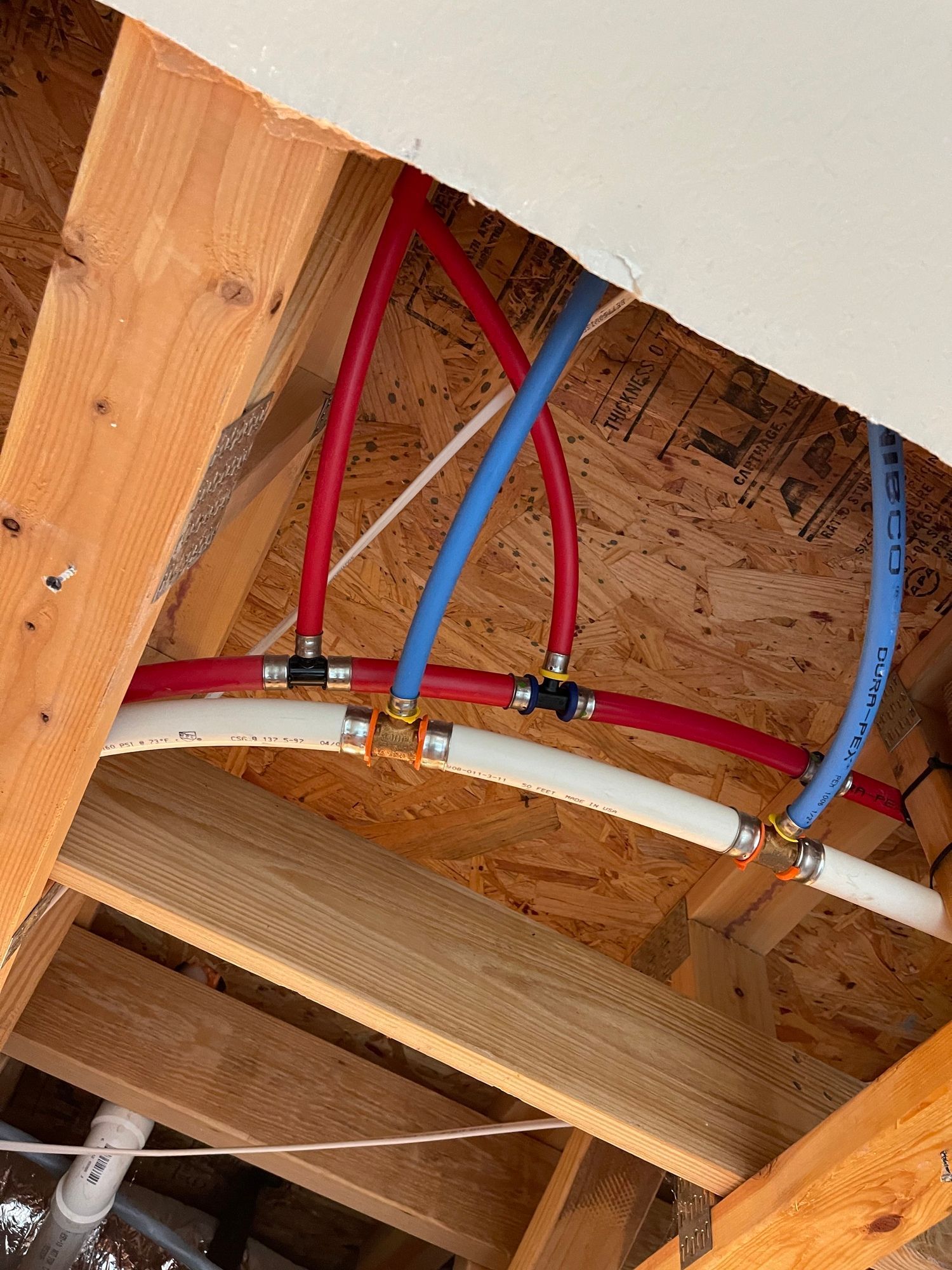 A bunch of pipes are hanging from the ceiling of a house.