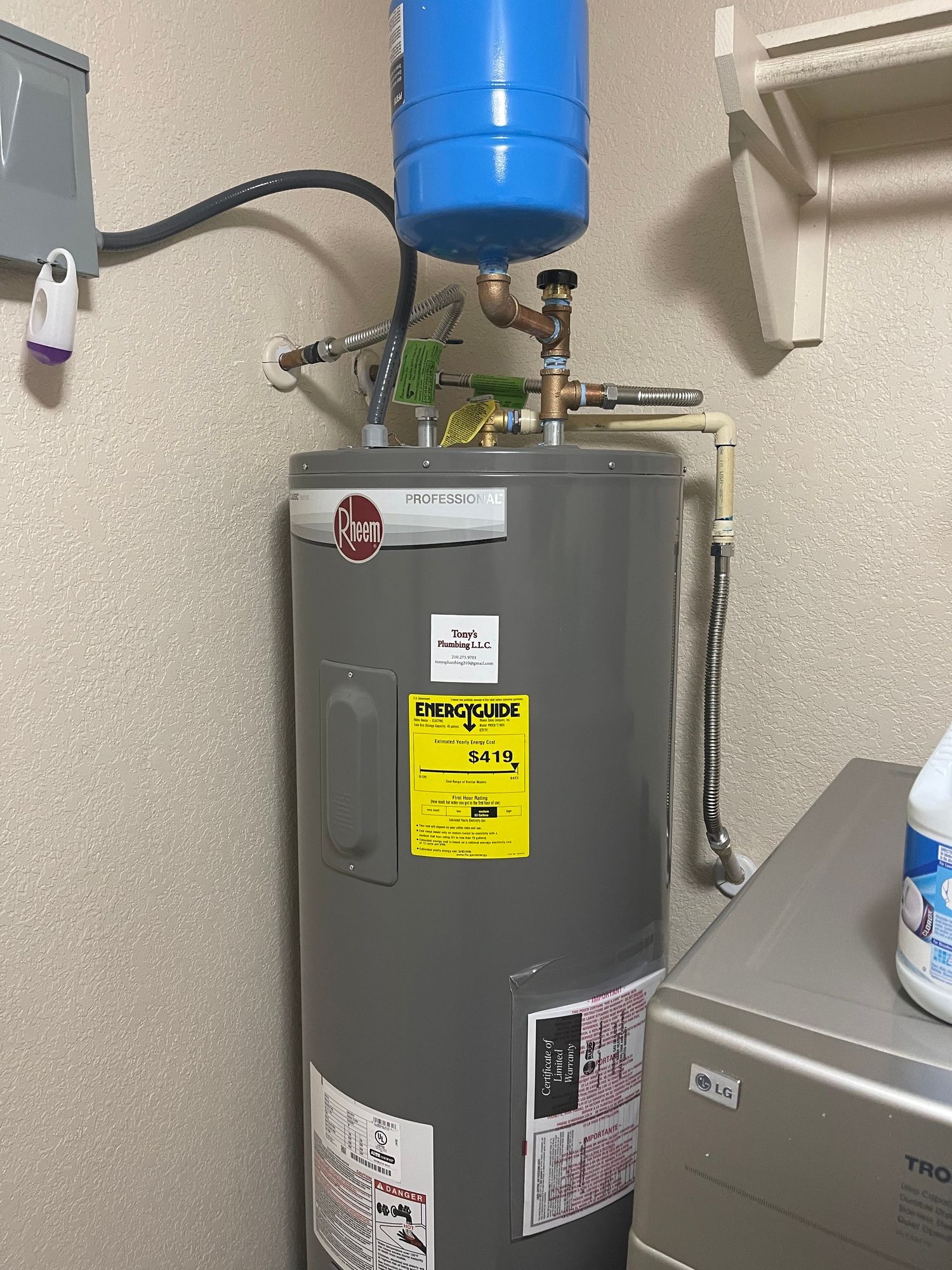 A water heater is sitting in a laundry room next to a washer and dryer.