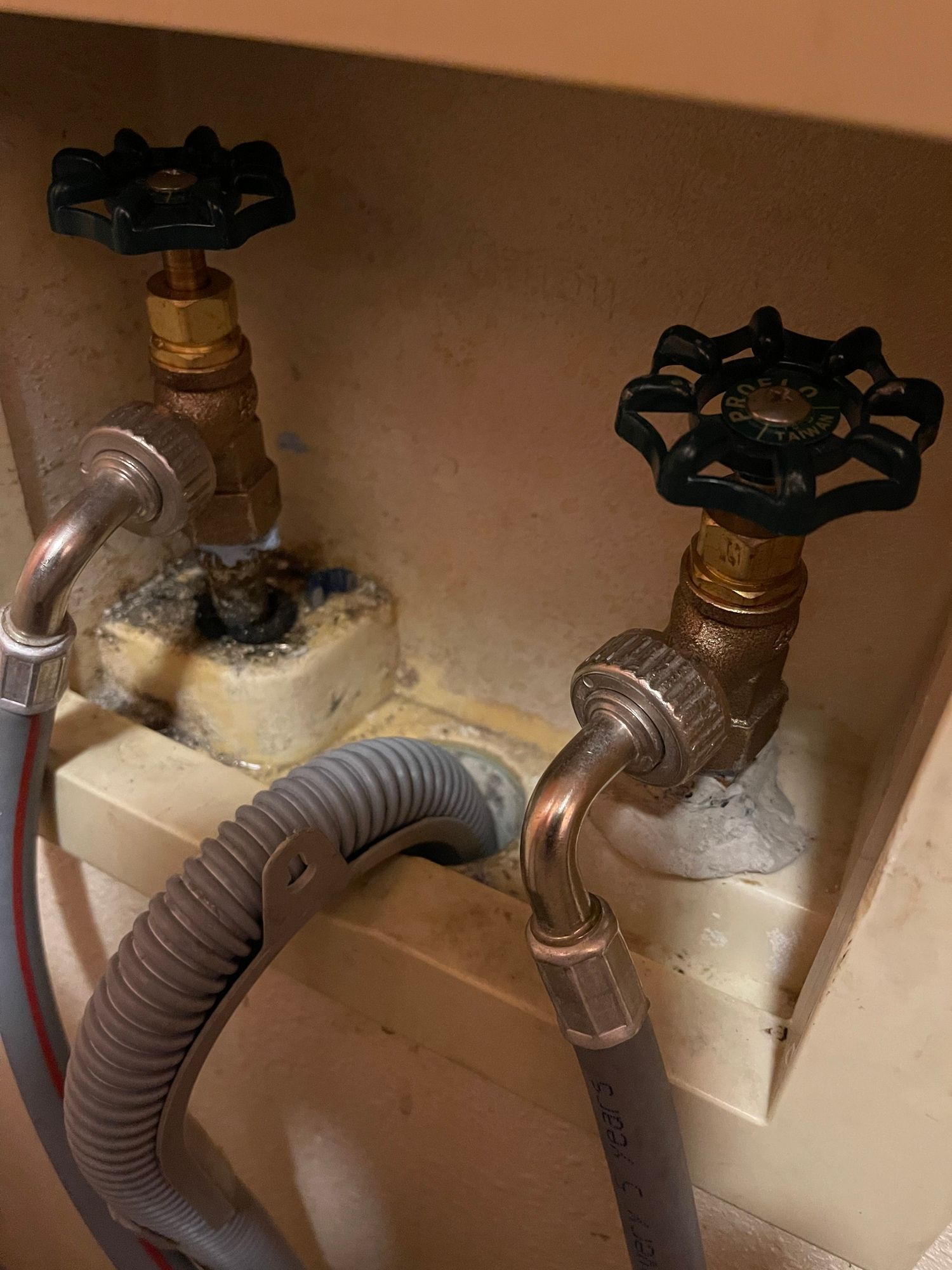 A close up of a hose and valves in a bathroom.