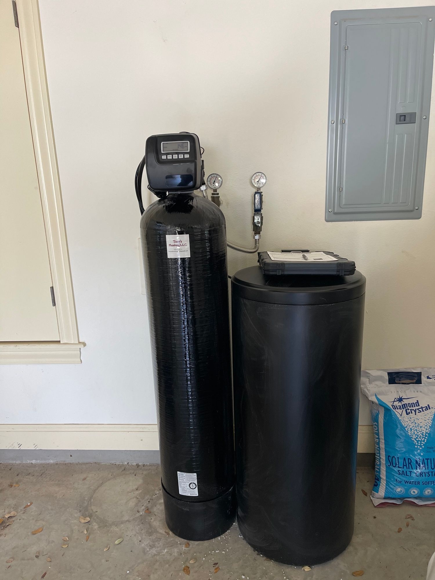 A black water filter is sitting next to a black tank in a garage.