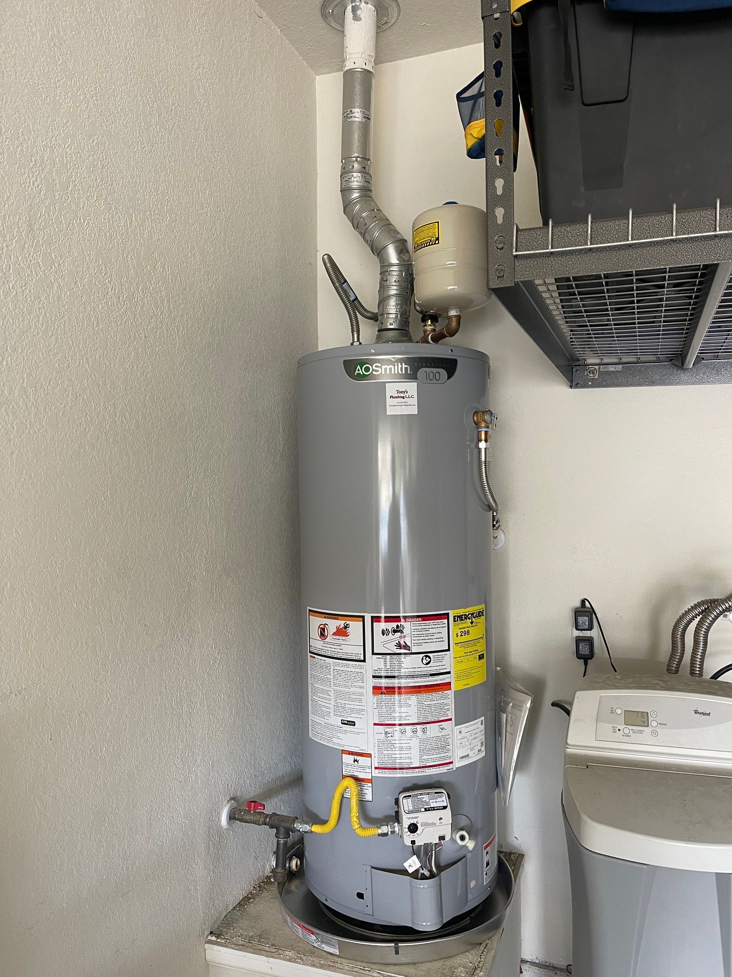 A water heater is sitting on top of a sink in a laundry room.