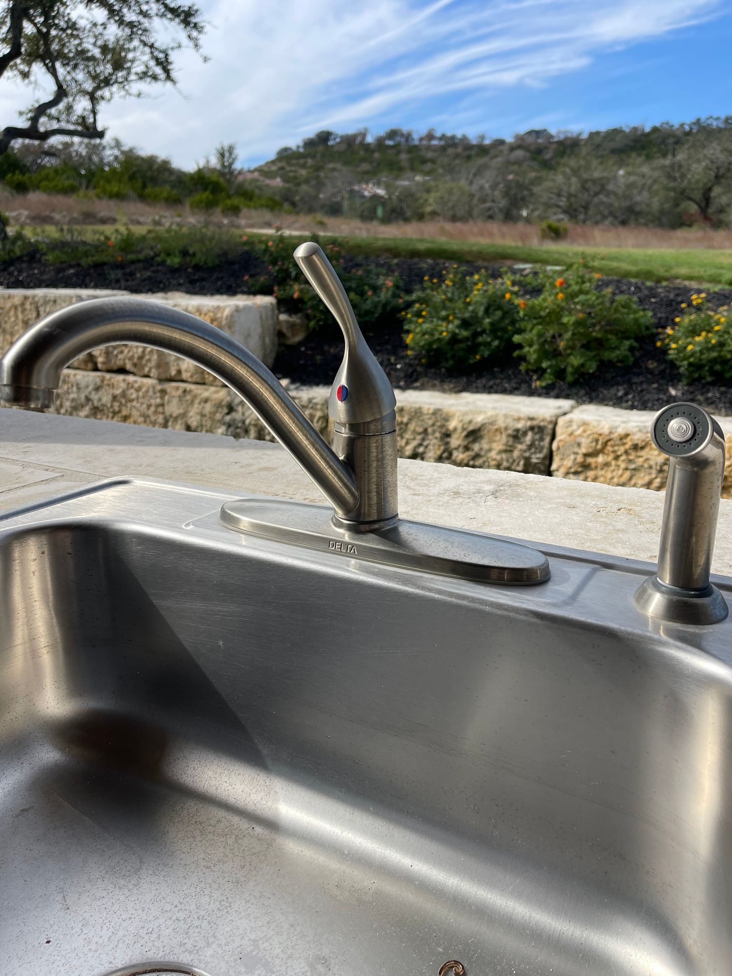 A close up of a stainless steel kitchen sink with a faucet.