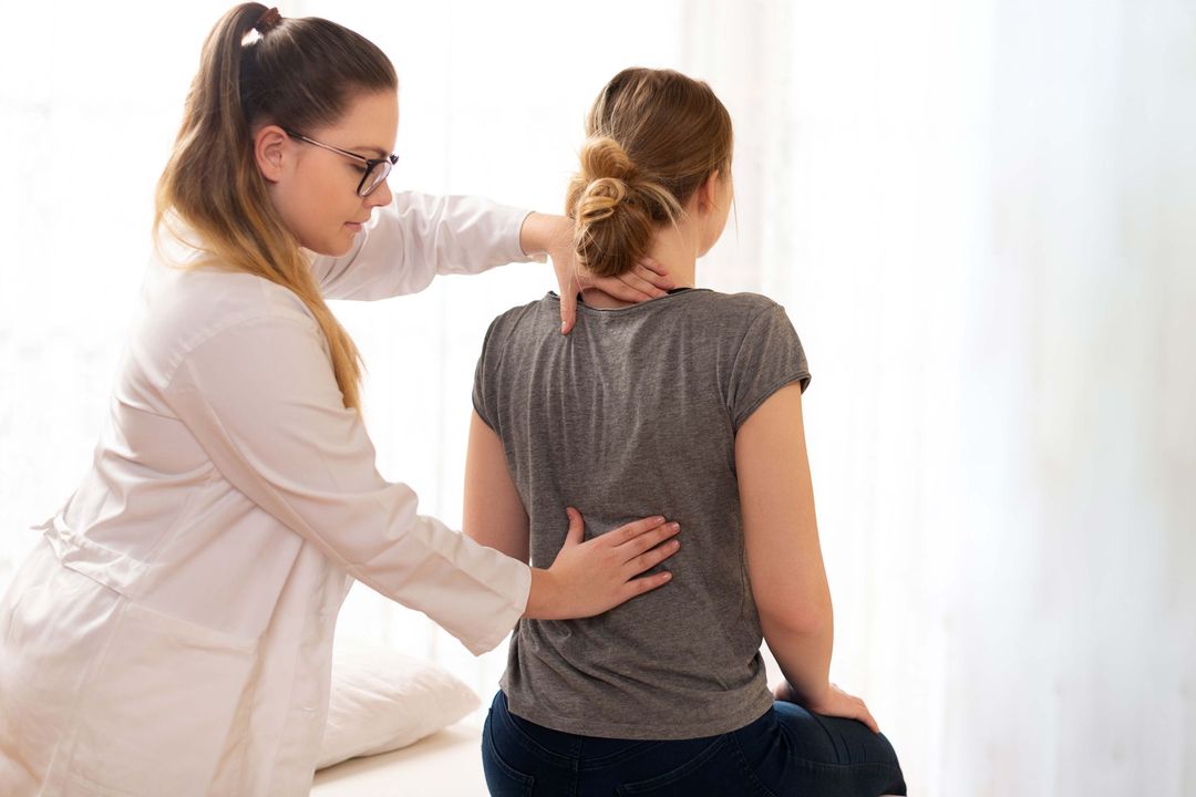 Female physiotherapist or a chiropractor examining patients back. Physiotherapy, rehabilitation concept.