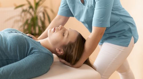 Female physiotherapist or a chiropractor adjusting patients neck